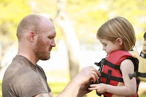 Dad fastening child's life vest