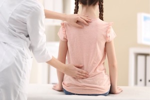 Doctor checking child's spine