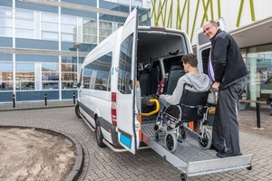 Woman helping man on wheelchair to get into an anambulance